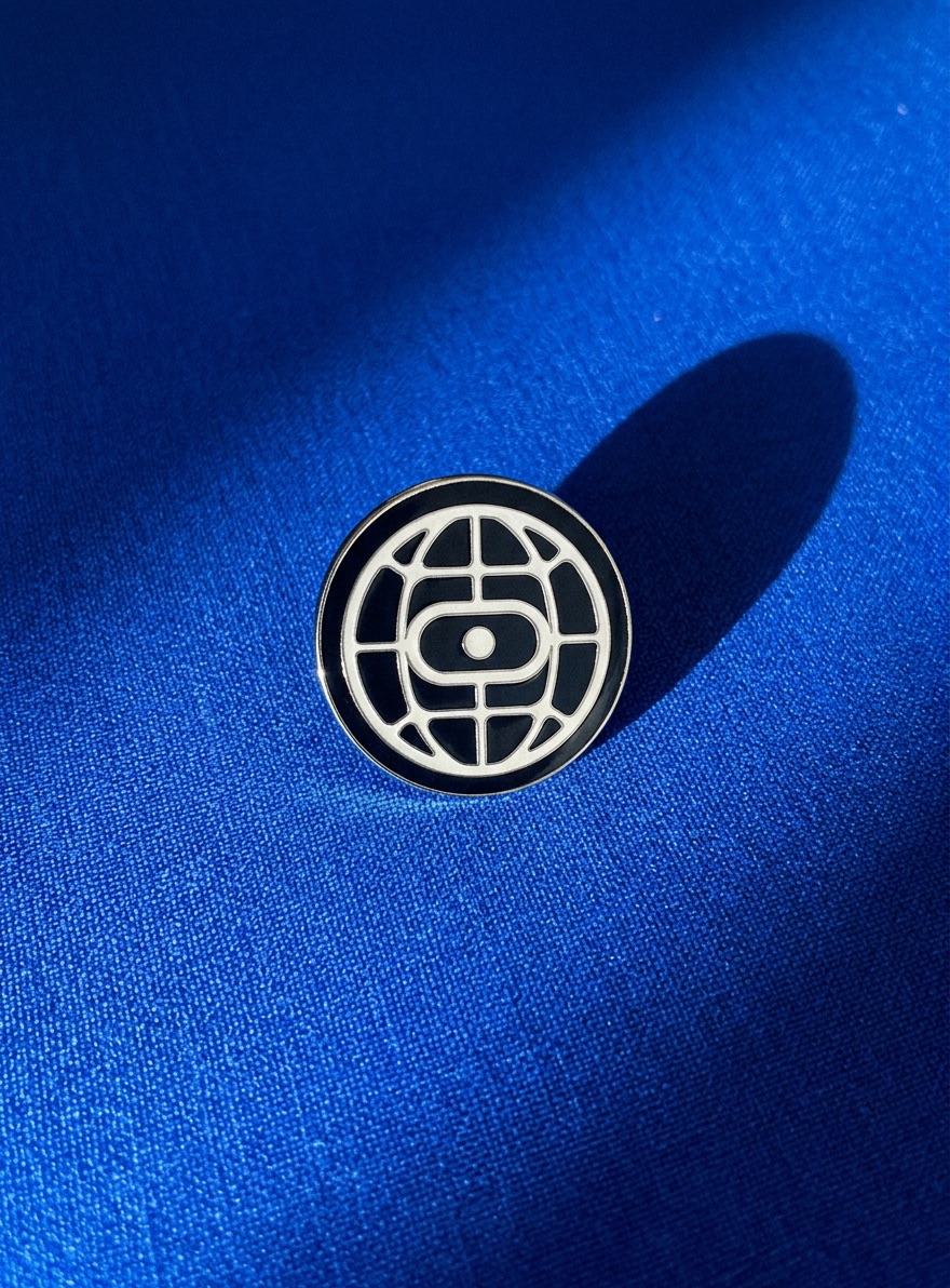 Enamel globe pin on blue fabric